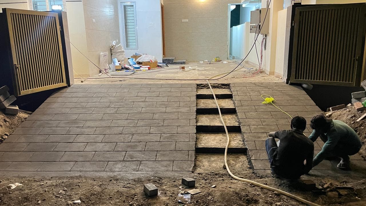 Workers laying stone-pattern paver flooring at the entrance driveway
