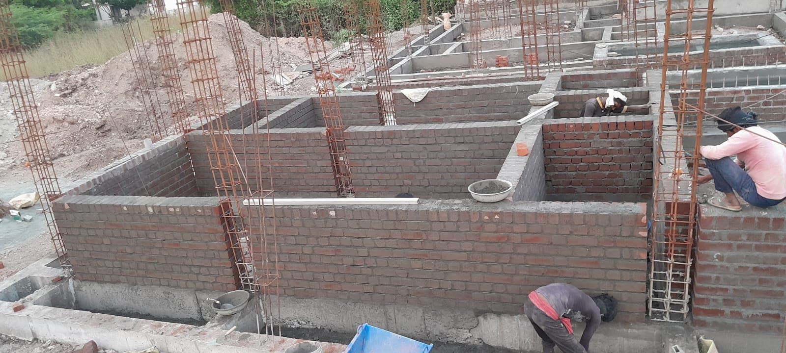 Brick walls rising between reinforced concrete columns at plinth level