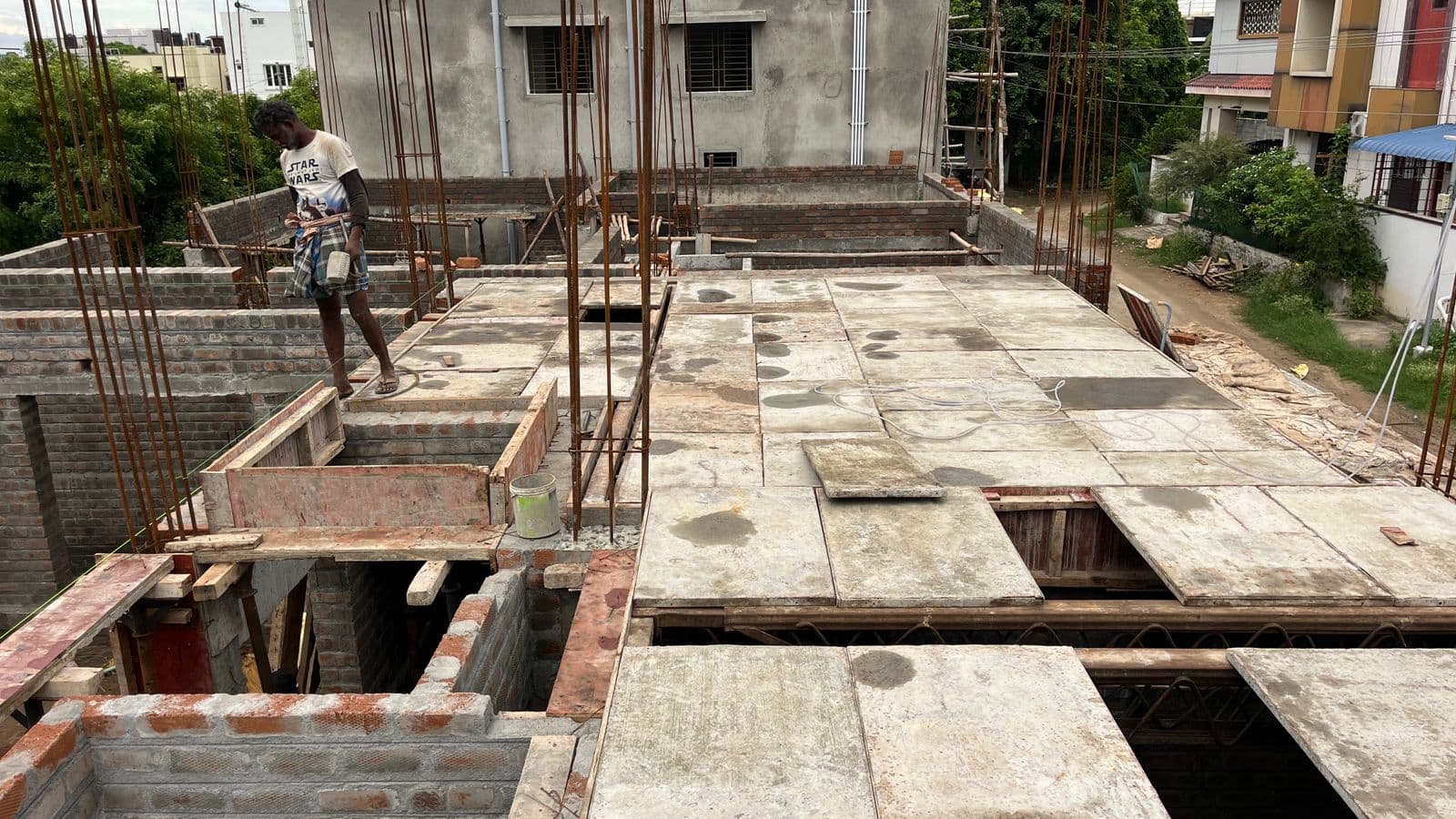 Worker on the first-floor roof slab with shuttering plates and reinforcement bars