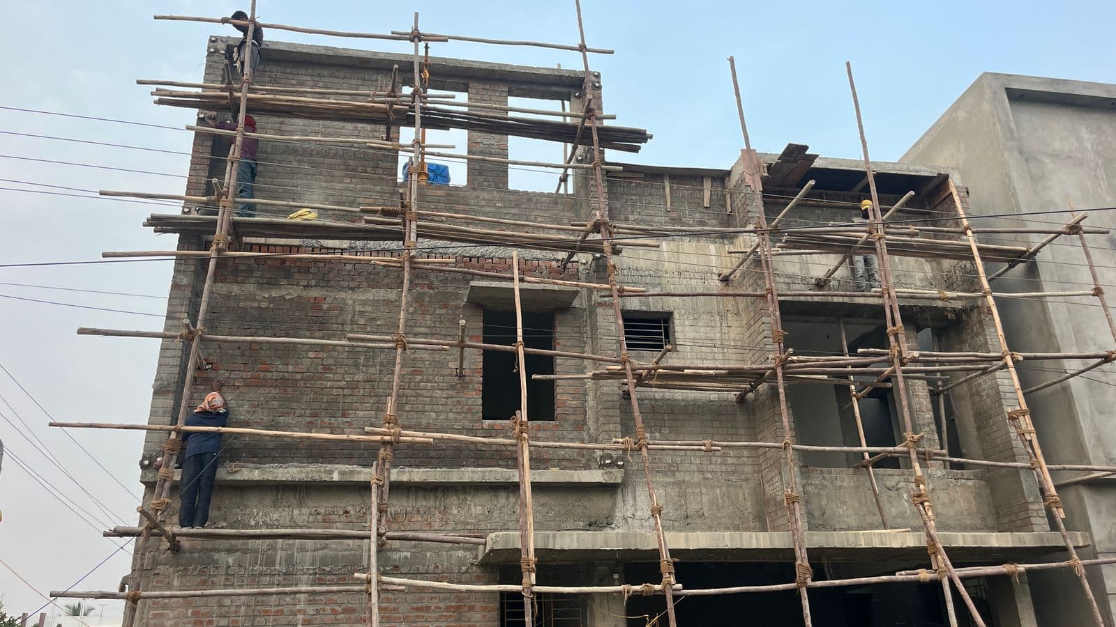 Brick facade under bamboo scaffolding during upper-floor construction