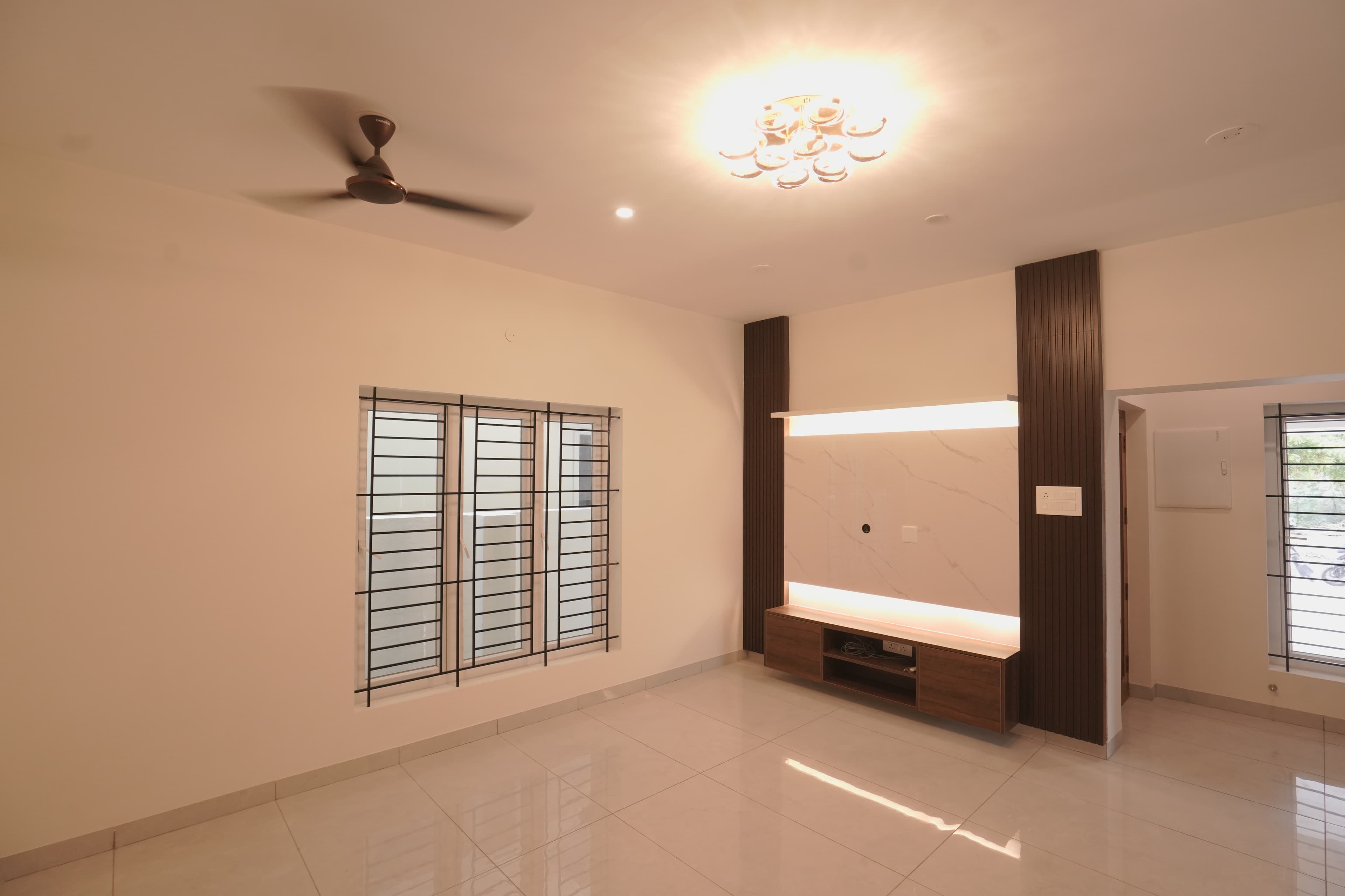 Living hall with a fluted timber TV wall, ceiling fan and chandelier