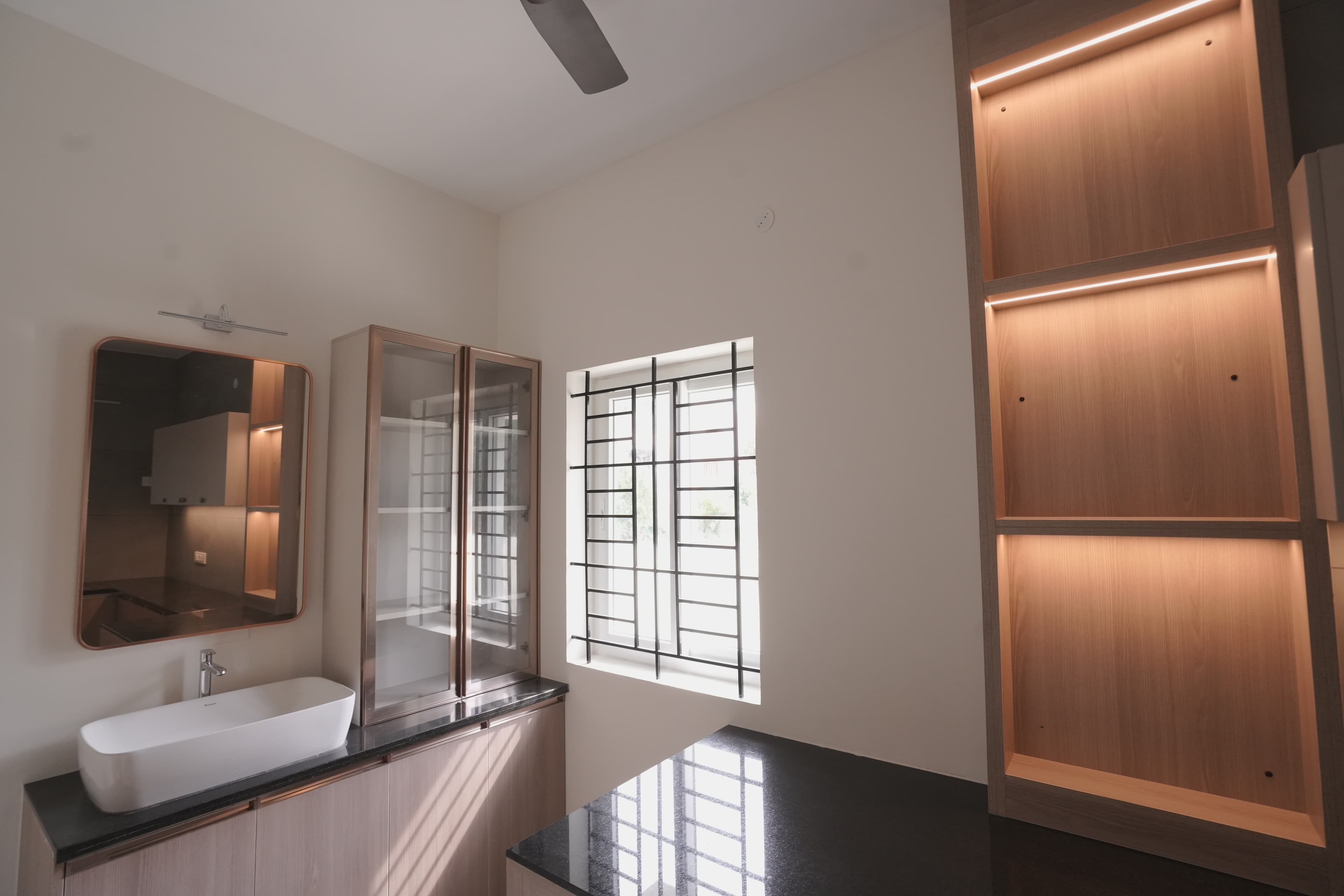Vanity with a vessel basin and mirror beside a lit timber niche
