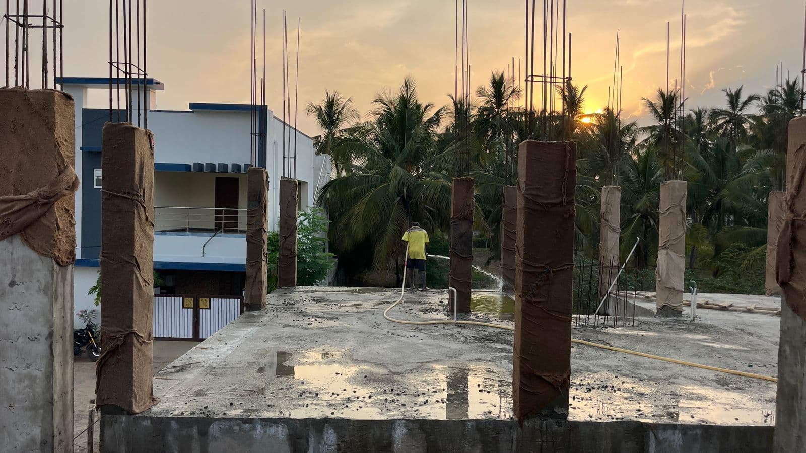 Columns in timber formwork on the slab at sunset, neighbouring houses beyond
