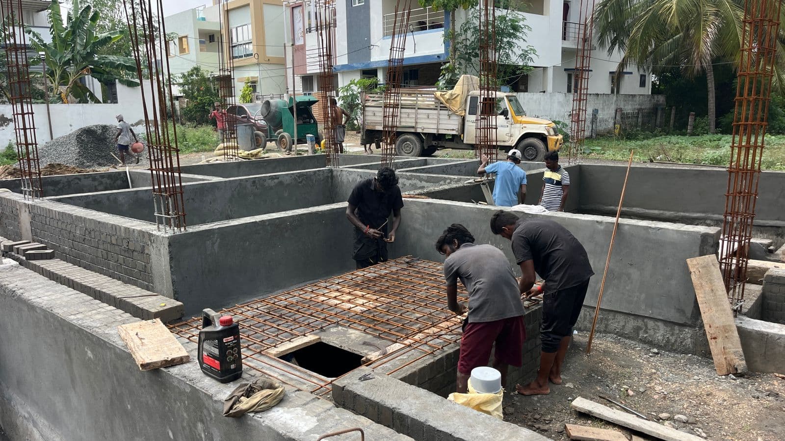 Workers tying reinforcement over a sunken pit between brick walls
