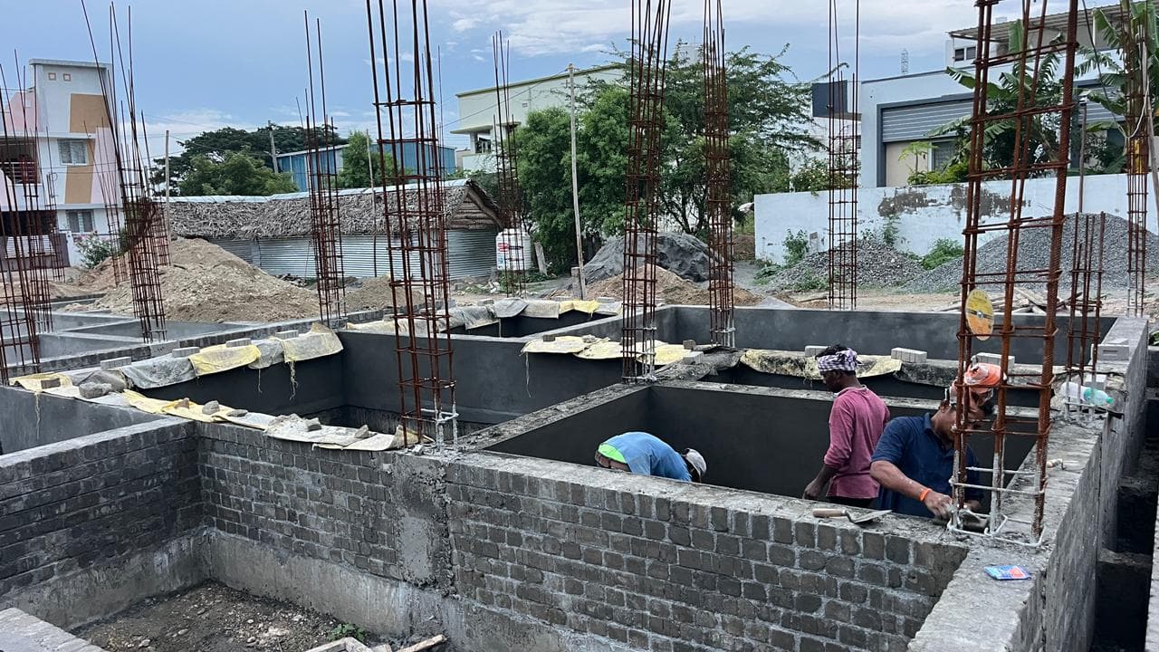 Workers coating the inside walls of a brick tank between reinforced columns