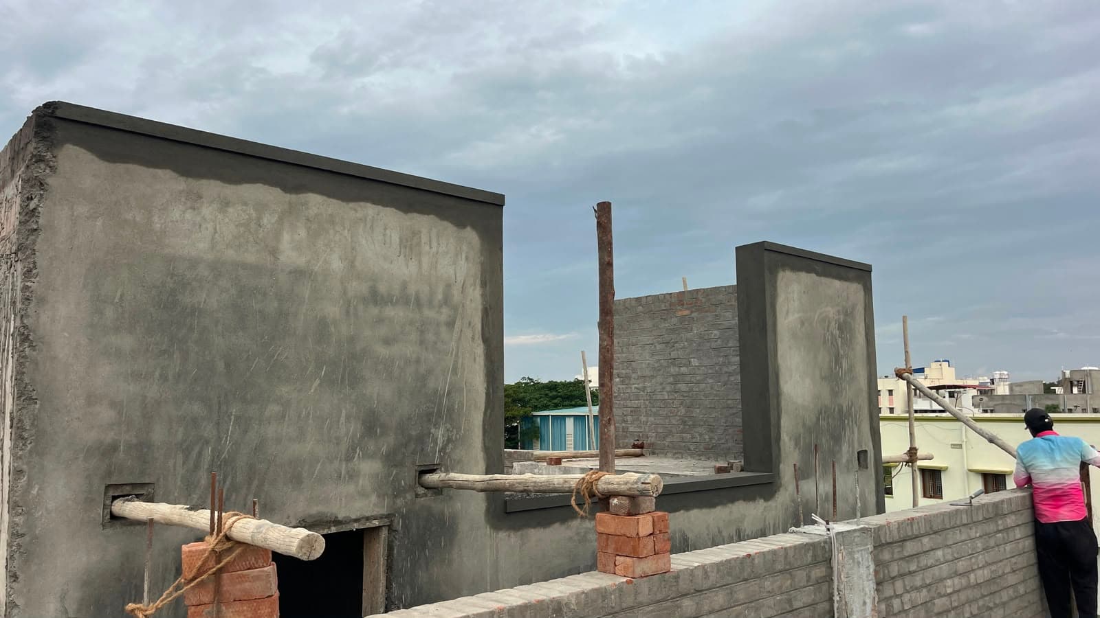 Plastered terrace parapet and stair-head room, a worker at the roof edge