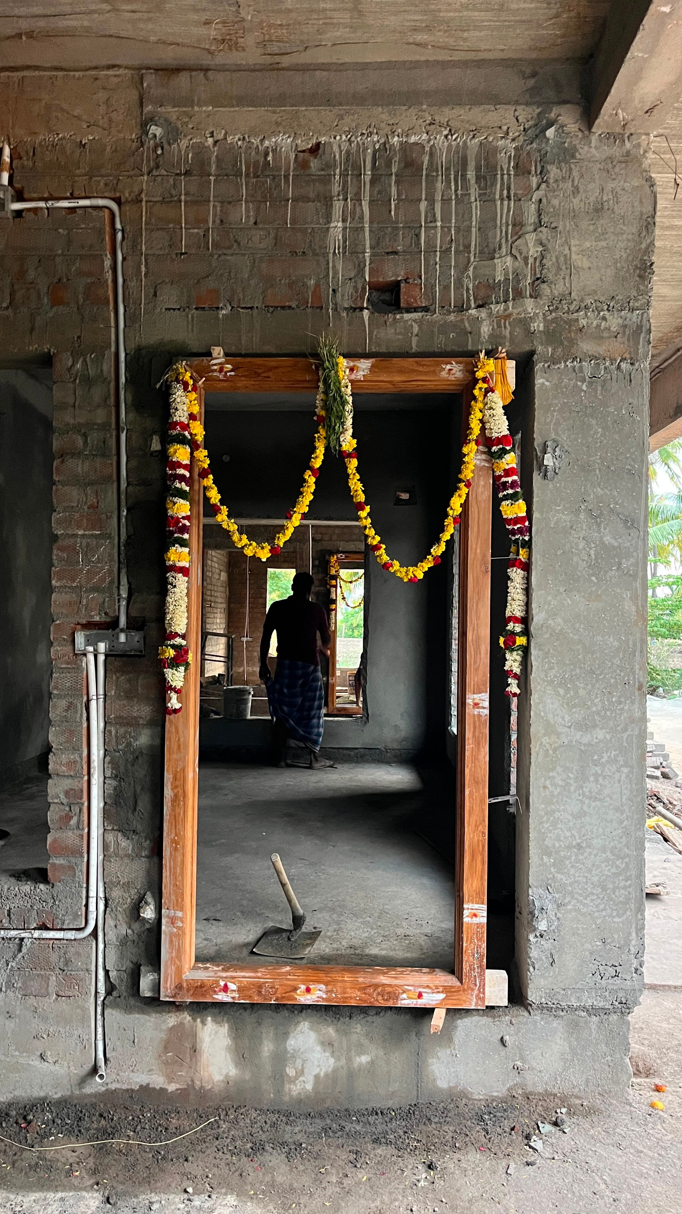 Timber door frame fixed in the concrete structure, hung with flower garlands