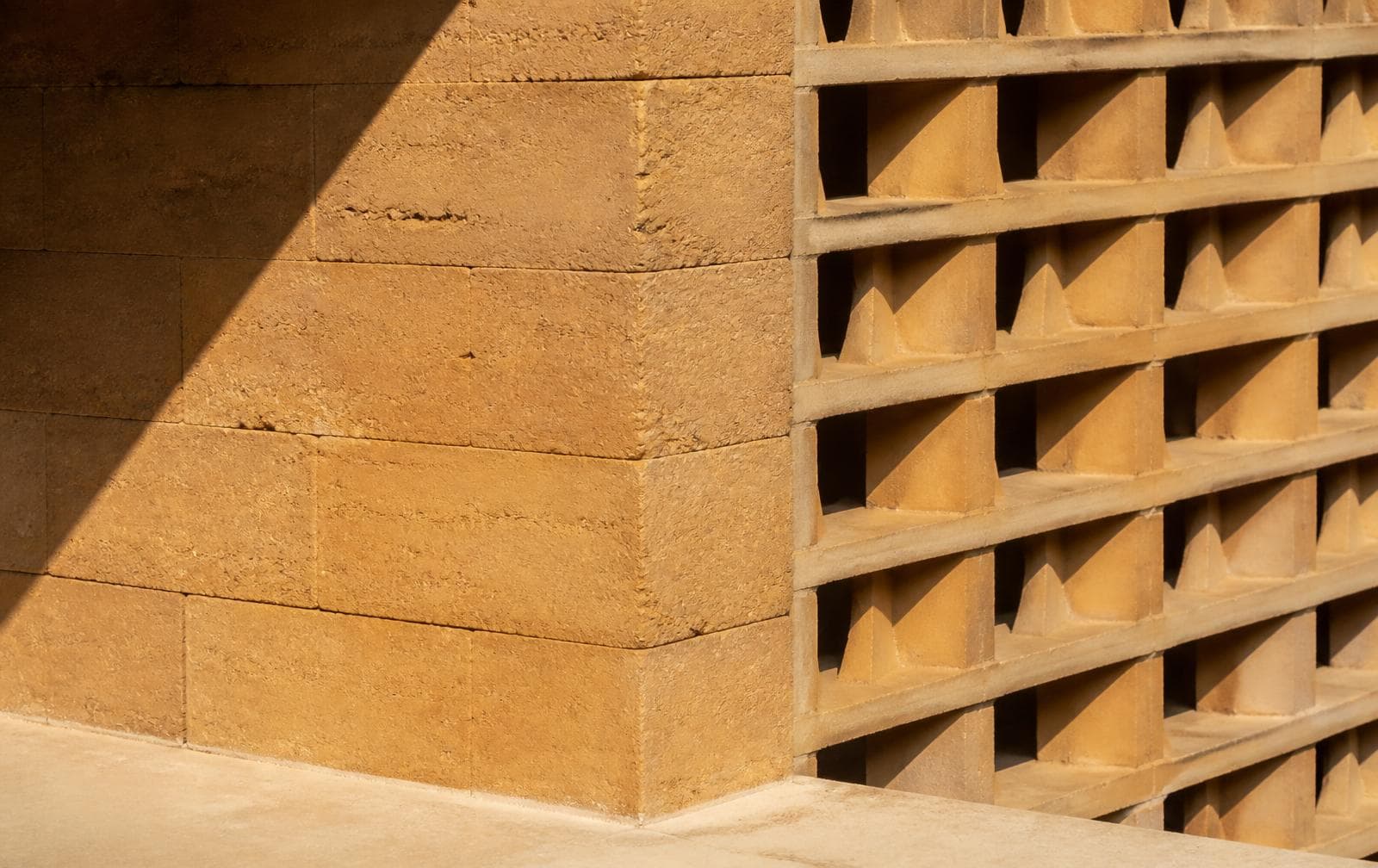 Earthen masonry and a perforated screen shown in direct sunlight